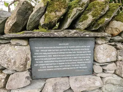 a stone sign on a rock wall with moss at Scale Force in Keswick