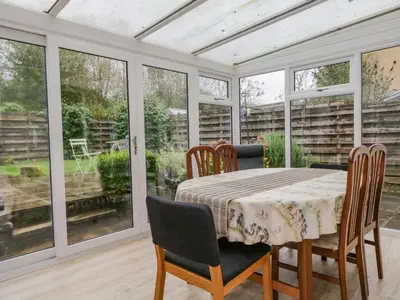 a conservatory with a table and chairs and windows at Ravenglass Retreat in Ravenglass