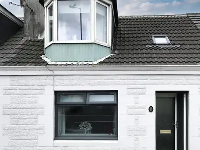 a white house with a window and a black door at Kitty's Cottage in Girvan