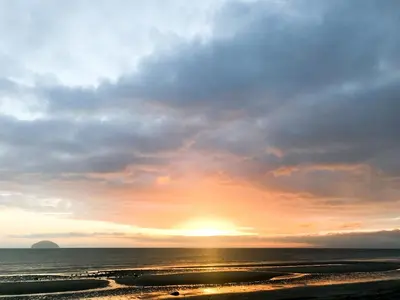 a sunset on the beach with the sun setting at Kitty's Cottage in Girvan
