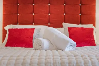 a bed with two towels and two red pillows at Cottage 3 Old Farmhouse Mews in Keswick