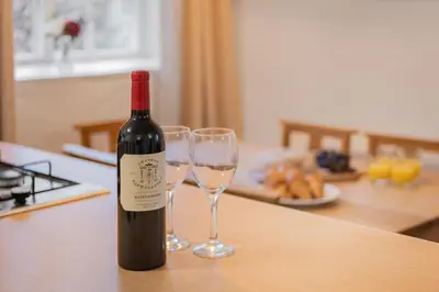 a bottle of wine sitting on a table with two wine glasses at Cottage 3 Old Farmhouse Mews in Keswick