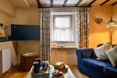 a living room with a blue couch and a window at Finest Retreats - The Cottage at Greystoke in Greystoke