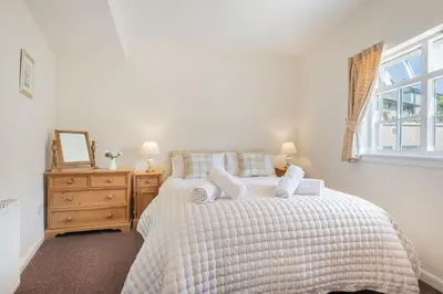 a bedroom with a bed with white sheets and a window at Cottage 8 Old Farmhouse braithwaite in Keswick