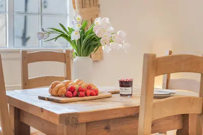 a table with a plate of fruit and a vase with flowers at Cottage 8 Old Farmhouse braithwaite in Keswick