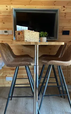 a table with two chairs in front of a tv at Craigend Farm Holiday Pods - The Curly Coo in Dumfries