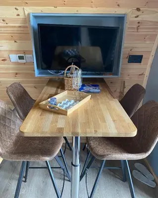 a wooden table with chairs and a tv in a room at Craigend Farm Holiday Pods - The Curly Coo in Dumfries