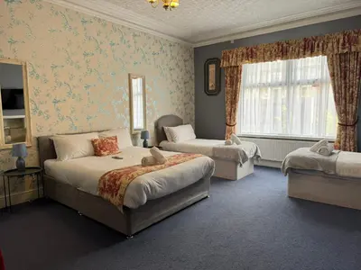 a bedroom with two beds and a couch and a window at The Calder House Hotel in Seascale