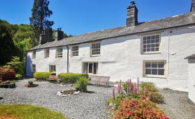 a white building with a bench in front of it at Seatoller House in Borrowdale Valley
