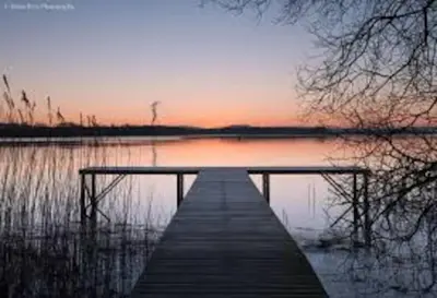 a dock on a body of water at sunset at Courtyard Cottage in Lockerbie