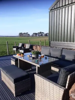 a patio with a table and chairs on a deck at Courtyard Cottage in Lockerbie