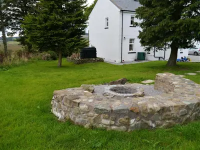 a stone fire pit in the yard of a house at Glaisters Farmhouse in Castle Douglas