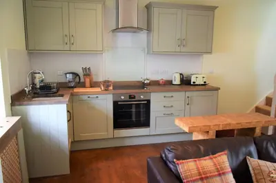 a kitchen with white cabinets and a stove top oven at Grooms Cottage in Carsethorn
