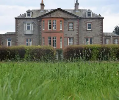 an old house in a field of tall grass at Grooms Cottage in Carsethorn