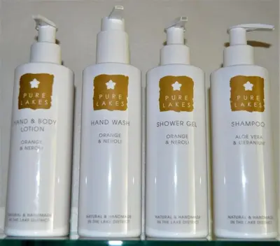 a group of four white shampoo bottles on a shelf at Woolpack Lodge in Holmrook