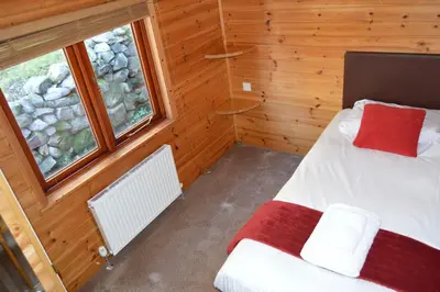 a small room with a bed and two windows at Woolpack Lodge in Holmrook