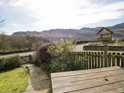 a wooden bench with a bird house on a fence at Fellside View in Ambleside