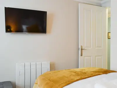 a bedroom with a bed with a television on the wall at Willow Cottage in Cockermouth