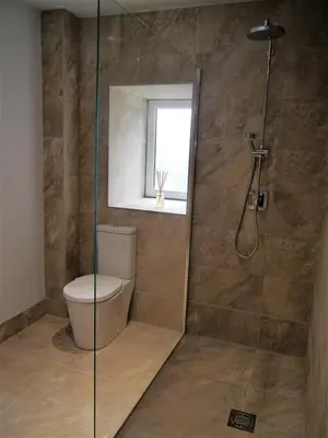 a bathroom with a shower with a toilet and a window at Waterfall in Castle Douglas