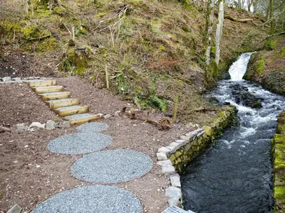 a walkway next to a river with a stream at Waterfall in Castle Douglas