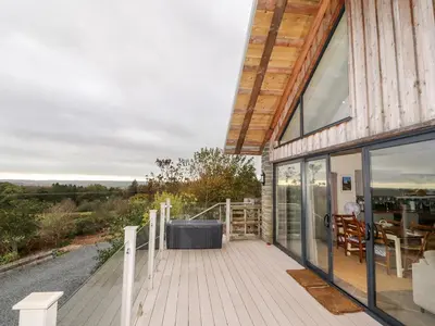 a house with glass doors and a deck with a table at The Lodge in Stranraer