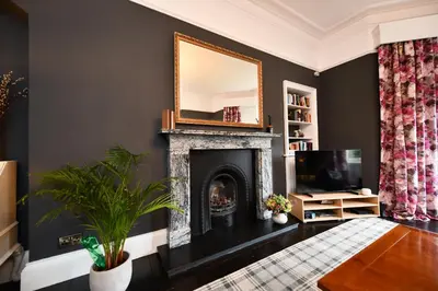 a living room with a fireplace and a mirror at The Old Manse in Ayr