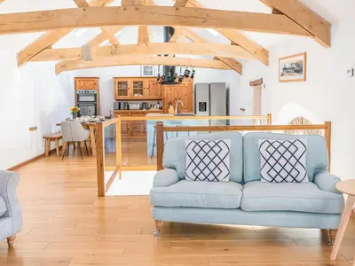 a living room with a blue couch and a kitchen at Swallow Barn in Cockermouth