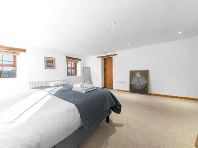 a bedroom with a large bed in a white room at Swallow Barn in Cockermouth