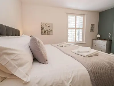 a bedroom with a white bed with two towels on it at Derwent Cottage in Keswick