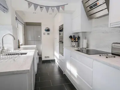 a kitchen with white cabinets and a black floor at Derwent Cottage in Keswick