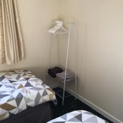 a bedroom with a bed and a towel rack next to a wall at Bobs plac in Whitehaven
