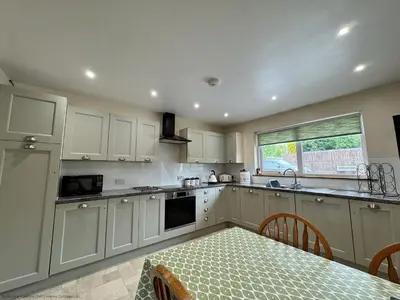 a kitchen with white cabinets and a table and a window at Croftdean in East Barcloy