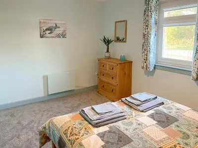 a bedroom with a bed and a dresser and a window at Ardwell Park in Ardwell