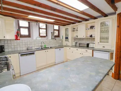 a kitchen with white cabinets and a large counter top at Old School Muncaster House in Ravenglass