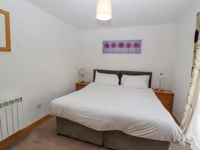 a bedroom with a large bed with white sheets at Old School Muncaster House in Ravenglass