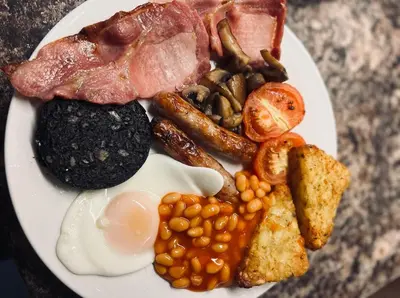 a plate of breakfast food with eggs beans and bacon at Ashleigh House in Carlisle