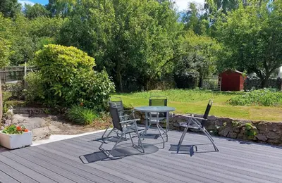 a patio with a table and chairs on a deck at Springfield in Dalbeattie