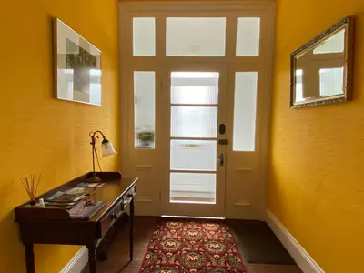 a yellow room with a door and a table and a rug at St John's Flat Spacious Accomodation in Dalry