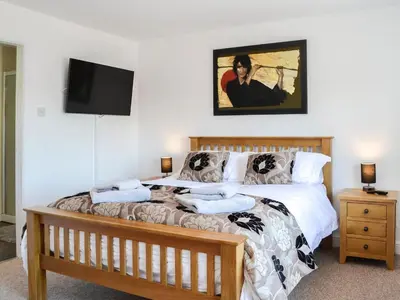 a bedroom with a bed and a flat screen tv at The Byre - Camp Douglas - Cottage in Crossmichael