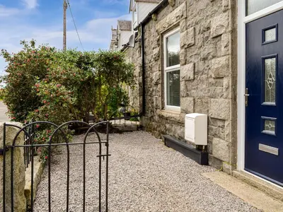 a house with a blue door and a bush at Park Crescent - Cottage in Creetown