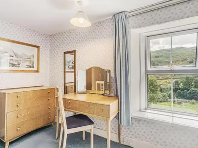a bedroom with a wooden desk and a window at High Rakes in Glenridding