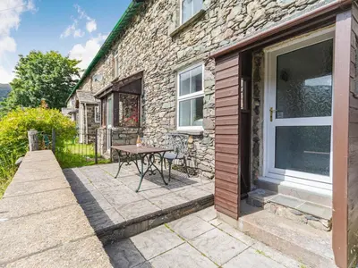 a stone house with a patio with a table at High Rakes in Glenridding