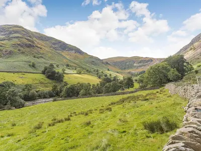 a view of a field with mountains in the background at High Rakes in Glenridding