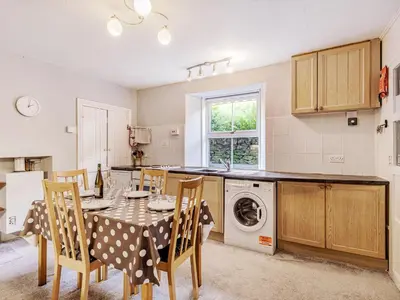 a kitchen with a table and chairs and a washing machine at High Rakes in Glenridding