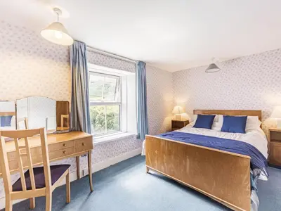 a bedroom with a bed and a desk and a window at High Rakes in Glenridding