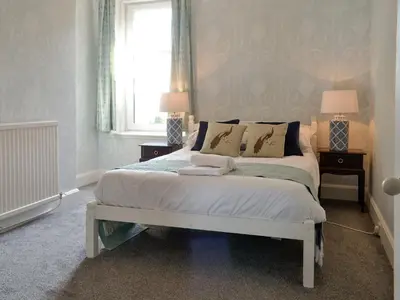 a bedroom with a bed with two lamps and a window at Cardoness Houses in Dumfries