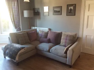 a couch sitting in a living room with a window at Cardoness Houses in Dumfries
