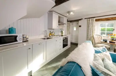 a kitchen with white cabinets and a blue couch at Bank View in Chapel Stile