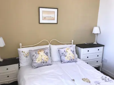 a bedroom with a bed with white sheets and pillows at Curlew Cottage and Sunset View in Port Logan