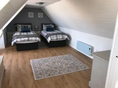 a attic room with two beds and a rug at Curlew Cottage and Sunset View in Port Logan